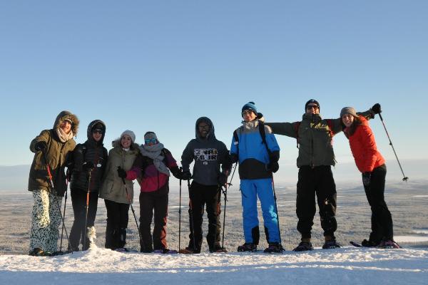 Eine Gruppe von Erasmus-Studierenden mit Schneeschuhen auf einem Hügel in Finnland