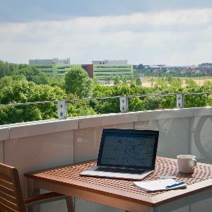 Aufnahme einer Terrasse und einem Tisch, auf dem eine Tasse und ein Laptop stehen