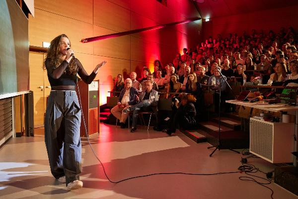Female speaker in front of an audience in a lecture hall