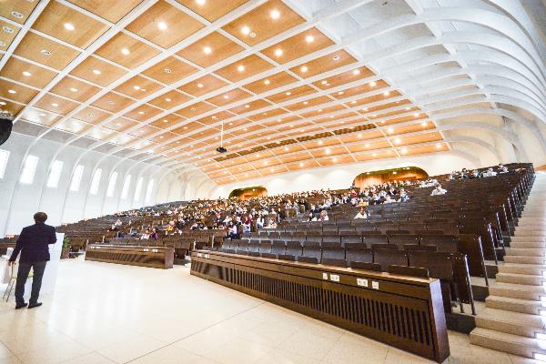 Blick in einen großen Hörsaal voller Studierenden während einer Vorlesung.