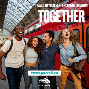 Group of four laughing students standing on a railway platform at a station