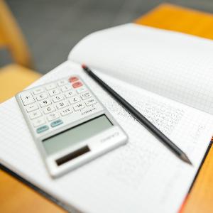 Schreibtisch mit Taschenrechner, Notizbuch und Stift