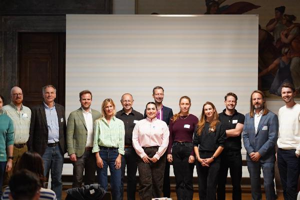 Gruppenfoto der Teilnehmenden des LMU Innovators Forum in München: Forschende, Gründerinnen und Gründer sowie Vertreter der LMU Entrepreneurship-Initiative stehen gemeinsam im Hörsaal vor der Leinwand.