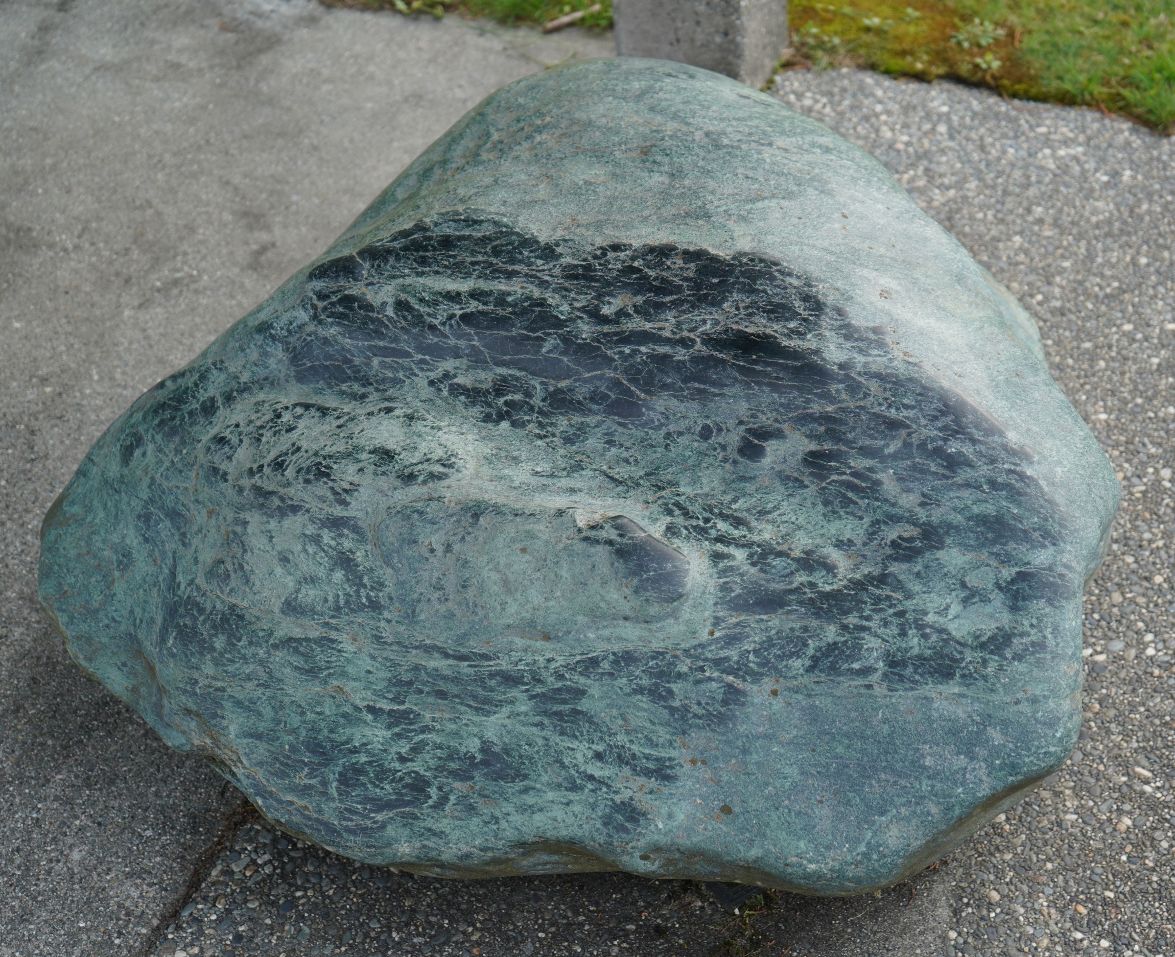 Ein großer Pounamu-Felsbrocken auf dem Pflaser des Gehwegs in Hokitika