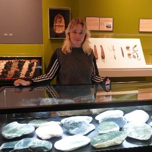Alina Berg im Museum hinter einer Vitrine mit Pounamu-Steinen