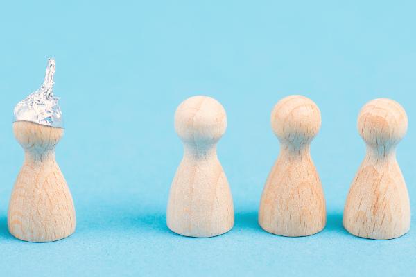 Drei Holzfiguren mit Alufolienhüten neben drei normalen Holzfiguren auf blauem Hintergrund.