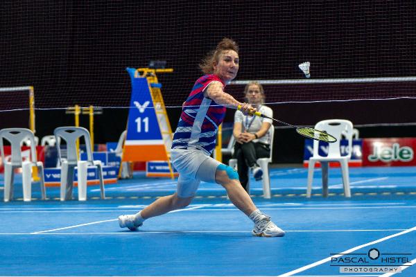 Tanja Eberl als Badminton-Spielerin in Aktion: Sie streckt sich nach vorne, um den Federball während eines Hallenspiels zu schlagen.