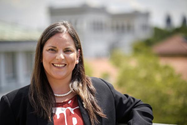 Professorin Marianela Fader steht auf dem Dach des Gebäudes Luisenstraße. Sie trägt eine rotweiß-gemusterte Bluse. Im Hintergrund ist verschwommen der Königsplatz zu sehen.