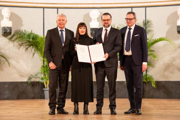 Munich Mayor Dieter Reiter, Carolin Amlinger, Oliver Nachwey, and Börsenverein Chairman Klaus Fürederder stand on stage at the official ceremony and jointly present an opened award document.