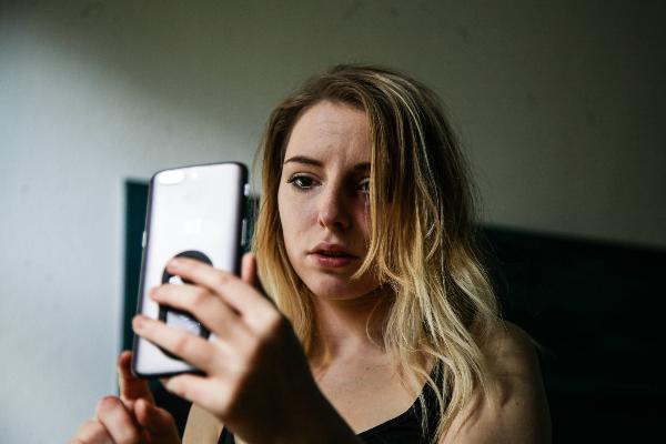 Young woman looking concerned at smartphone in dim room