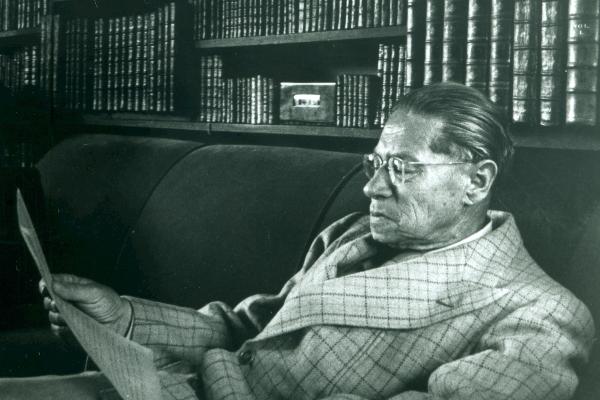 Lion Feuchtwanger in his late years in his library in the Villa Aurora in Pacific Palisades, USA. He is sitting and reading a handwritten paper, probably a letter.