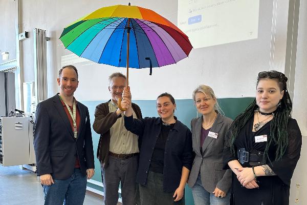 Teilnehmende am Lippsymposium posieren unter einem vielfarbigen Handschirm