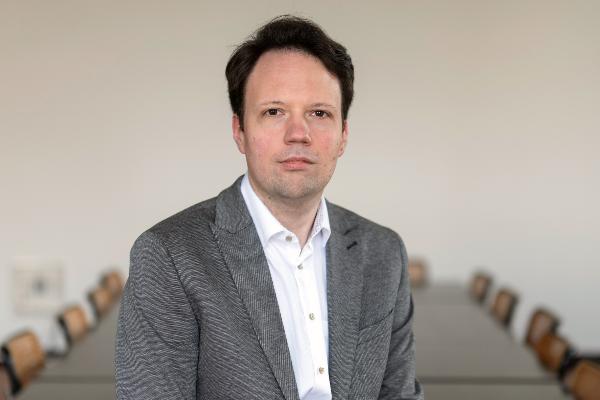 Professor Seewald im grauen Sakko in modernem Konferenzraum mit neutralem Hintergrund