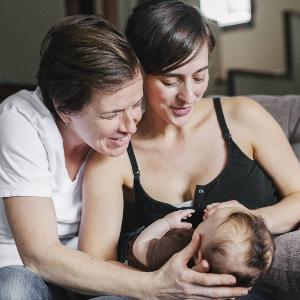 Queer family: Two mothers holding their baby in their arms.