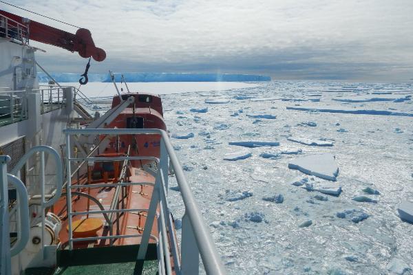 Research vessel in the Southern Ocean, iceberg in the background