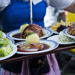 Kellnerin im Dirndl serviert bayerisches Essen