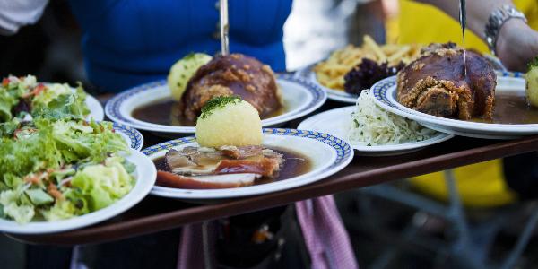 Kellnerin im Dirndl serviert bayerisches Essen | © picture alliance / Felbert+Eickenberg / STOCK4B / VisualEyze Kellnerin im Dirndl serviert bayerisches Essen