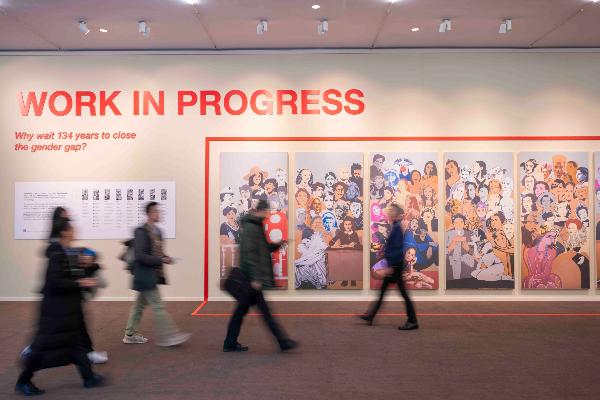 Passers-by walk along a billboard