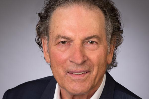 Professor Dieter Frey mit dunkelgrauem, lockigem Haar im dunklen Sakko und weißem Hemd vor neutralem grauem Hintergrund. Hochwertiges Bewerbungs- und Unternehmensporträt für Firmenwebsite, Presse, LinkedIn und Business-Kommunikation in Deutschland.