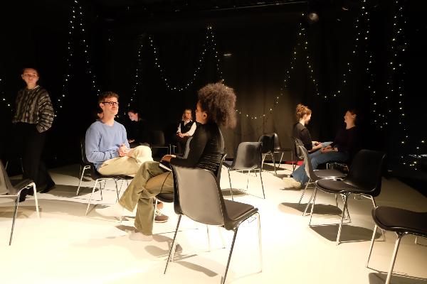Eine männliche und eine weibliche Person sitzen sich auf einer Theaterbühne gegenüber | © LMU Eine männliche und eine weibliche Person sitzen sich auf einer Theaterbühne gegenüber