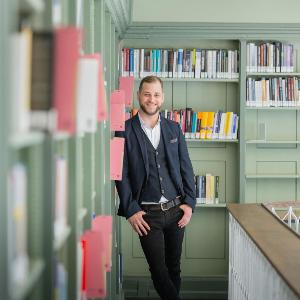 Porträt des Philosophen Timo Greger, Referent der KI Lectures, in einer Bibliothek