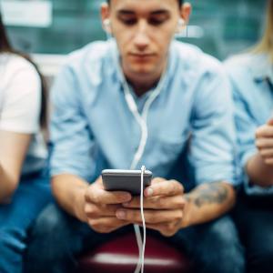 Jugendliche sitzen nebeinenader und blicken in ihre Smartphones