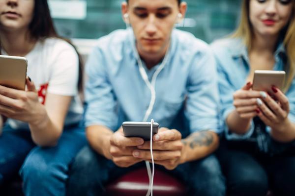 Jugendliche sitzen nebeinenader und blicken in ihre Smartphones