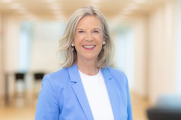 Dr. Katja Wildermuth wearing a blue blazer standing in a modern office hallway with a bright, professional setting