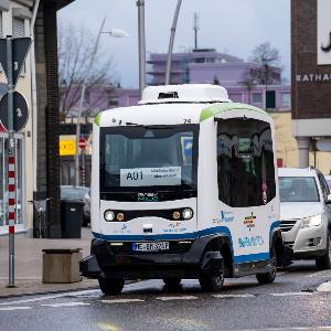 Autonom fahrender weißer Linienbus im Straßenverkehr