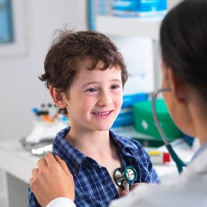 Eine Ärztin untersucht ein Kind mit einem Stethoskop.