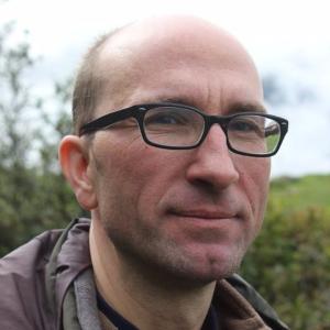 Professor Magnus Treiber, Brille, Halbglatze vor floralem, grünem Hintergrund