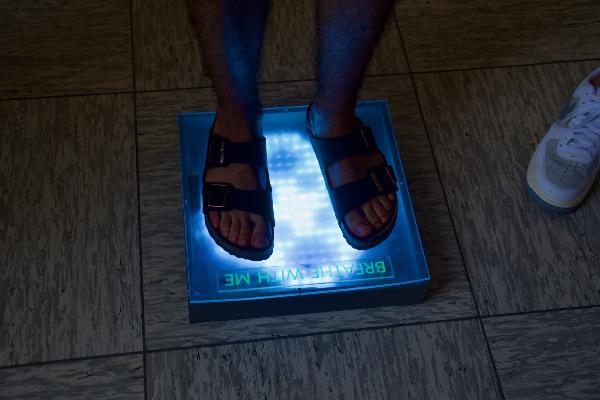 A person is standing on a glowing floor tile.