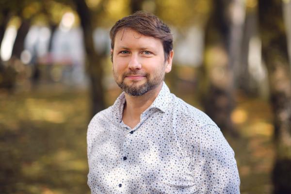 Alexander Wuttke stands in front of several trees