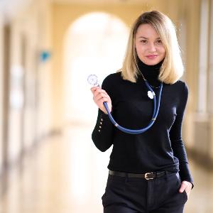 Deutschlandstipendiatin Valeriia Andrieieva steht mit einem Stethoskop im Hauptgebäude der LMU