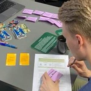 Two young men are leaning over a desk covered with Cassandra Method charts.