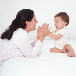 A mother claps her hands while playing with her child