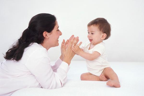 A mother claps her hands while playing with her child
