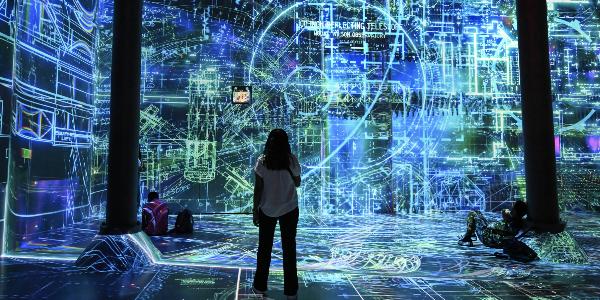 A woman stands in front of a large-scale work of art created with the help of artificial intelligence.