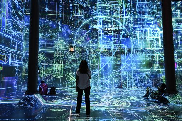 Eine Frau steht vor einem großflächigen mithilfe von Künstlicher Intelligenz geschaffenen Kunstwerk