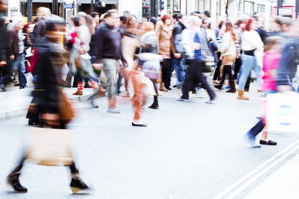 Menschen laufen mit Einkaufstüten durch eine Fußgängerzone.