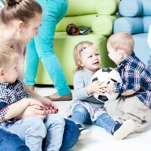 Two toddlers are fighting over a ball.