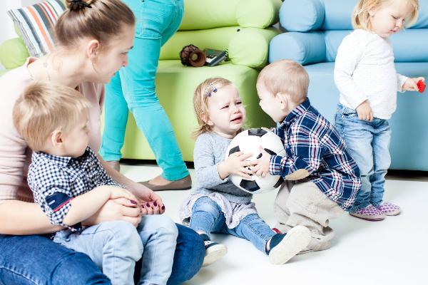 Two toddlers are fighting over a ball.