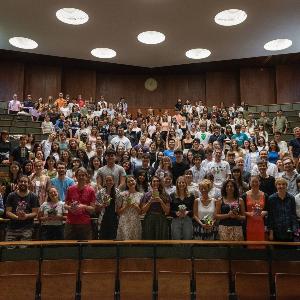 Studierende und Dozierende stehen zusammen in einem Hörsaal
