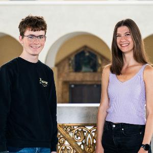Eine Sängerin und ein Sänger stehen nebeneinander ihm Hauptgebäude der LMU