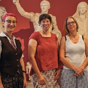 Drei Frauen stehen vor Abgüssen antiker Statuen im Museum.