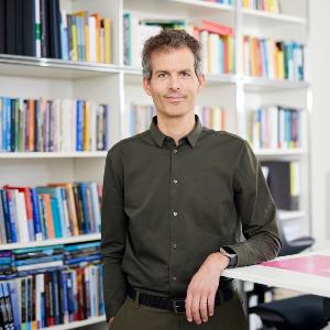 Prof. Berhold Rittberger steht vor einem Bücherregal