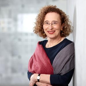 Prof. Monika Betzler steht an einer weißen Wand