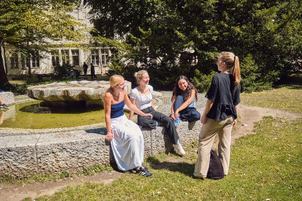 Studentinnen sitzen am Rand eines Brunnens.