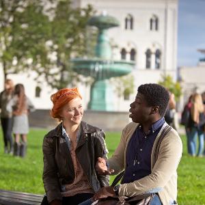 Studierende unterhalten sich vor dem Brunnen am Hauptgebäude der LMU