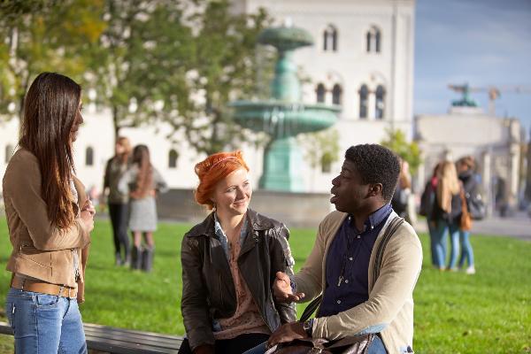 Studierende unterhalten sich vor dem Brunnen am Hauptgebäude der LMU